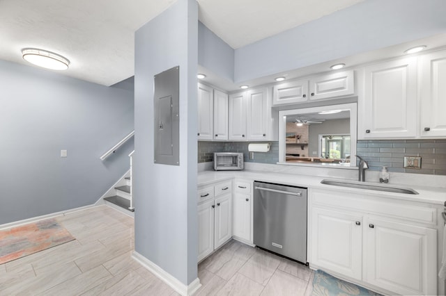 kitchen with stainless steel dishwasher, tasteful backsplash, a sink, light countertops, and white cabinets