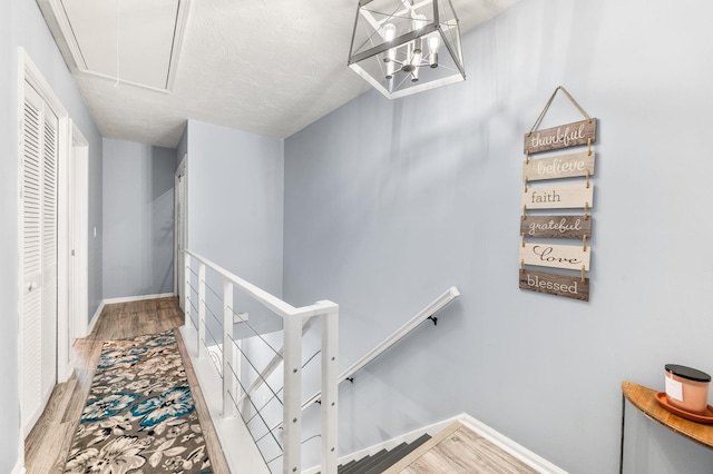 corridor featuring attic access, baseboards, wood finished floors, and an upstairs landing