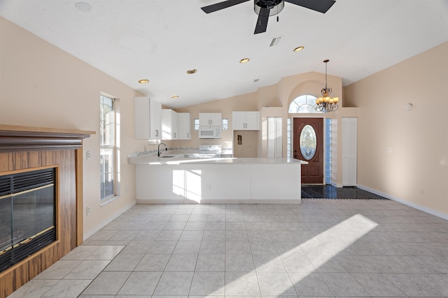 kitchen featuring kitchen peninsula, vaulted ceiling, white cabinets, light tile patterned floors, and white appliances