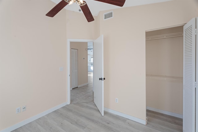 unfurnished bedroom featuring light wood-type flooring, a closet, vaulted ceiling, and ceiling fan