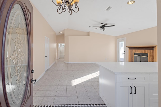 interior space featuring ceiling fan with notable chandelier, vaulted ceiling, white cabinets, and light tile patterned flooring