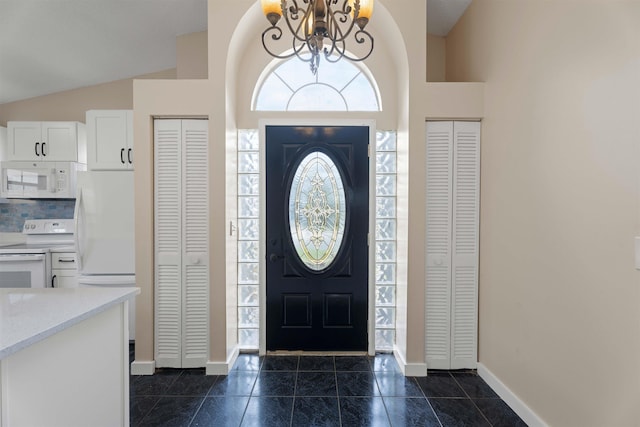 entryway with a chandelier, lofted ceiling, baseboards, and dark tile patterned flooring