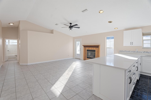 kitchen with white cabinets, light tile patterned floors, lofted ceiling, and a healthy amount of sunlight