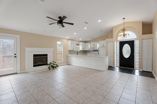 unfurnished living room featuring tile patterned floors, vaulted ceiling, a chandelier, a ceiling fan, and baseboards