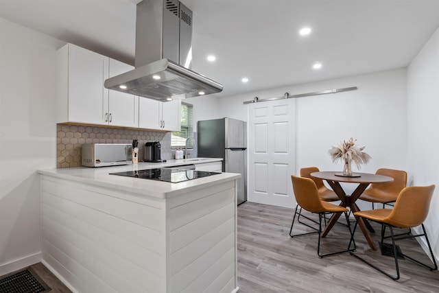 19 Phillips St, Saint Augustine, FL 32084 - kitchen featuring white microwave, freestanding refrigerator, island exhaust hood, light wood finished floors, and black electric cooktop