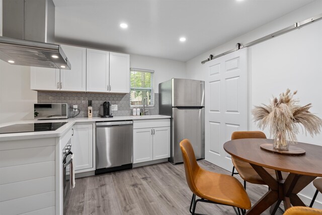 19 Phillips St, Saint Augustine, FL 32084 - kitchen featuring exhaust hood, white cabinets, black appliances, a sink, and light countertops