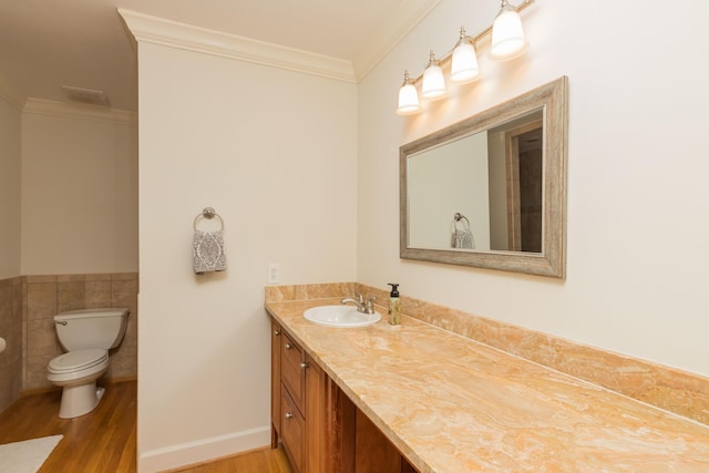 313 S Forest Dune Dr, Saint Augustine Beach, FL 32080 - bathroom with wood finished floors, vanity, crown molding, tile walls, and a wainscoted wall