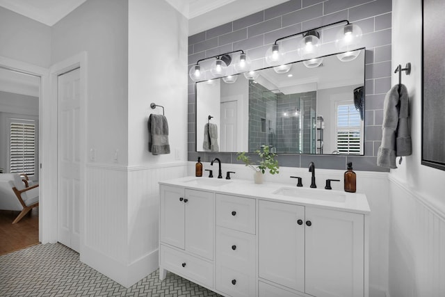 bathroom with a wainscoted wall, a stall shower, and a sink