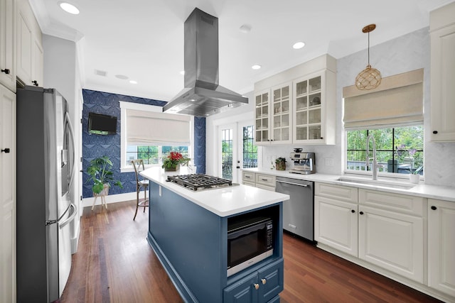 kitchen featuring wallpapered walls, appliances with stainless steel finishes, island range hood, blue cabinets, and a sink