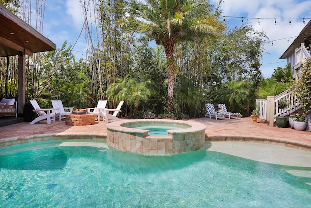 pool with a patio, a fire pit, and an in ground hot tub