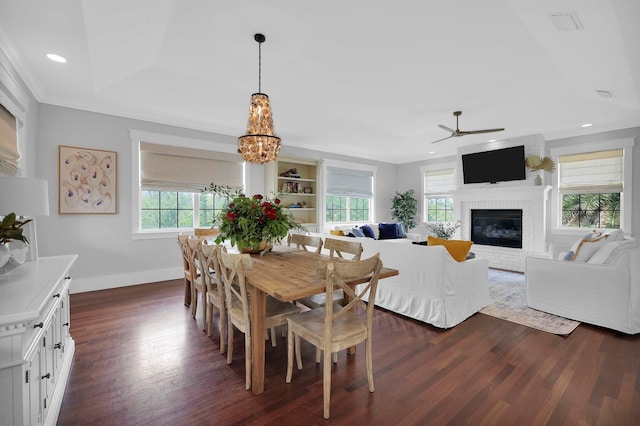 dining room featuring a brick fireplace, crown molding, baseboards, dark wood finished floors, and recessed lighting