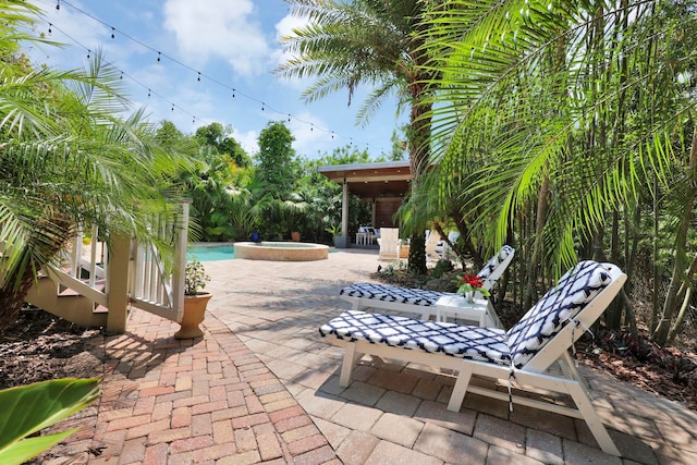 view of patio / terrace featuring an in ground hot tub and an outdoor pool