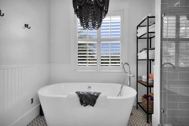 bathroom with a soaking tub and a wainscoted wall