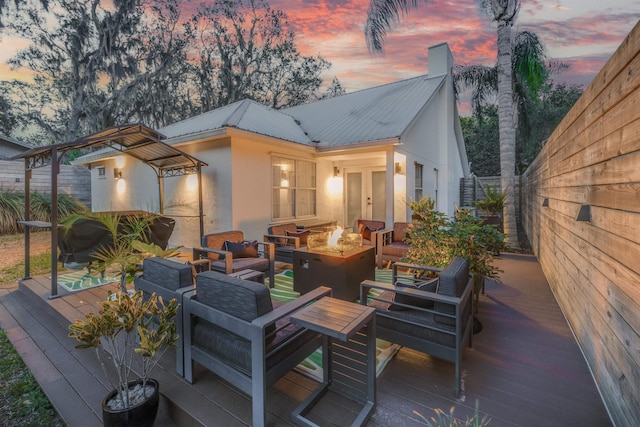 deck at dusk featuring an outdoor living space with a fire pit