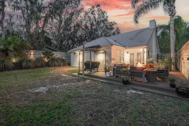 back house at dusk with a wooden deck, an outdoor hangout area, and french doors