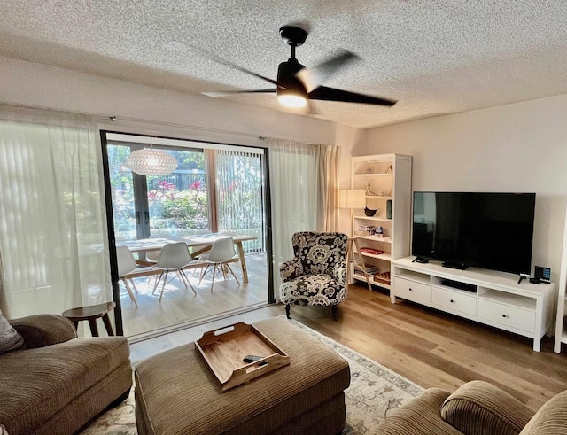 living room featuring hardwood / wood-style flooring, ceiling fan, and a textured ceiling