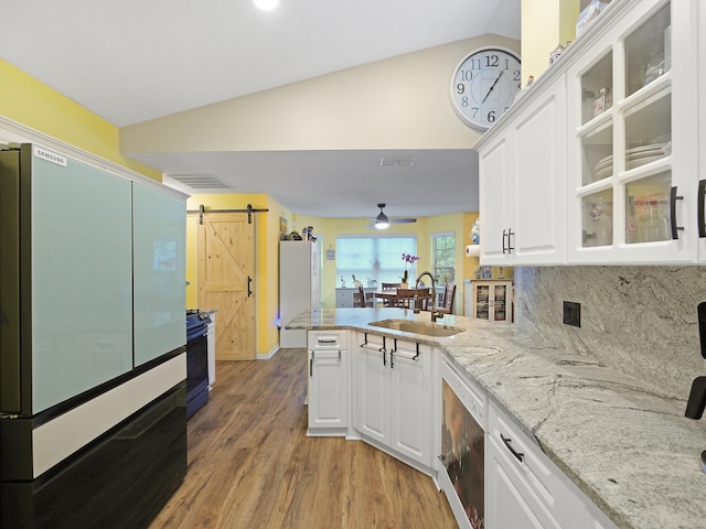 kitchen featuring a barn door, lofted ceiling, a sink, a peninsula, and fridge