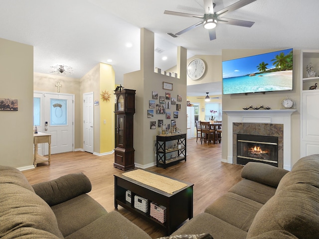 living room with baseboards, visible vents, lofted ceiling, a ceiling fan, and wood finished floors