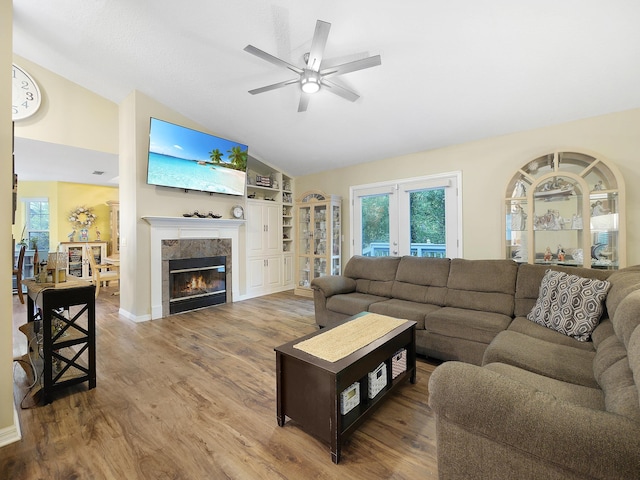 living area with lofted ceiling, a healthy amount of sunlight, wood finished floors, and ceiling fan