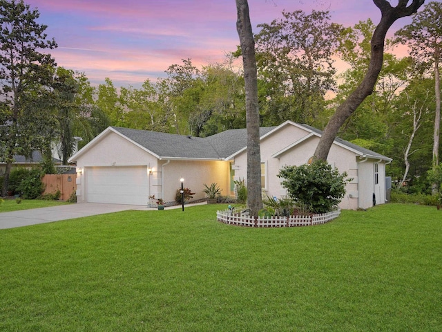ranch-style home featuring an attached garage, concrete driveway, a front yard, and stucco siding