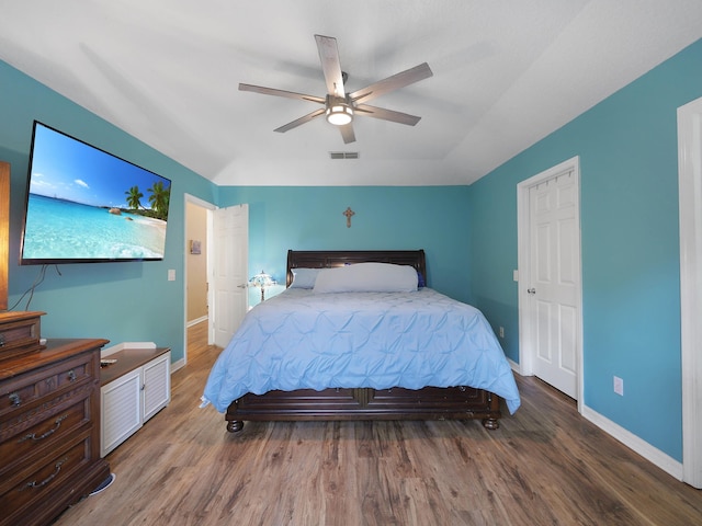 bedroom with wood finished floors, visible vents, a ceiling fan, and baseboards