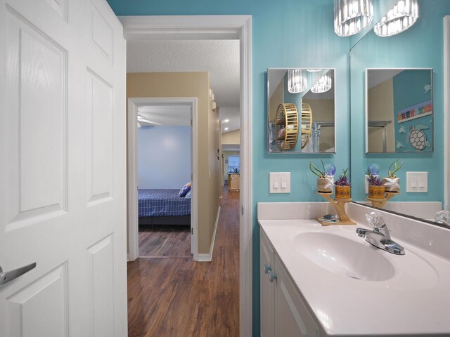 bathroom featuring baseboards, wood finished floors, ensuite bath, and vanity