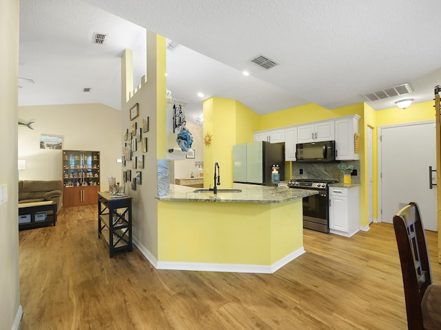 kitchen featuring visible vents, a sink, freestanding refrigerator, black microwave, and gas stove