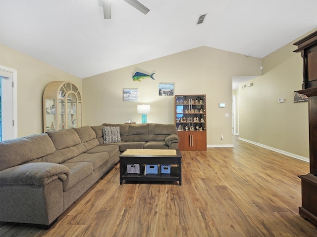 living area with a ceiling fan, wood finished floors, baseboards, lofted ceiling, and visible vents
