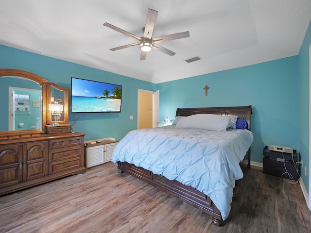 bedroom featuring wood finished floors, visible vents, a ceiling fan, and baseboards