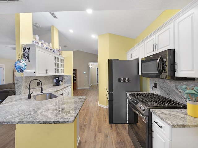 kitchen with wood finished floors, a sink, a peninsula, stainless steel appliances, and baseboards