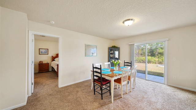 dining space featuring light carpet, a textured ceiling, and baseboards