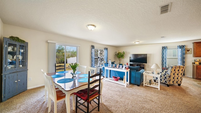 carpeted dining area with visible vents, a textured ceiling, and baseboards