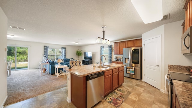 kitchen with a sink, open floor plan, light countertops, appliances with stainless steel finishes, and an island with sink