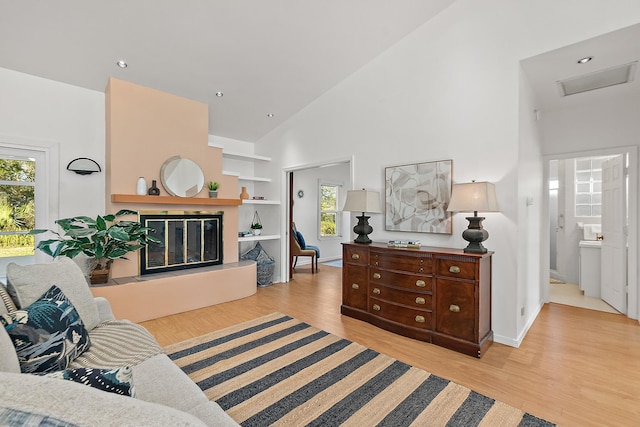 10 Marshview Dr, Saint Augustine, FL 32080 - living room featuring attic access, plenty of natural light, light wood-style floors, high vaulted ceiling, and a glass covered fireplace