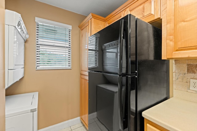 kitchen featuring light brown cabinets, light tile patterned floors, tasteful backsplash, and black fridge