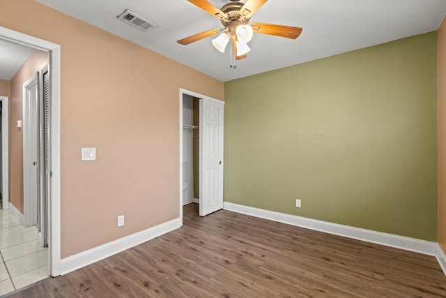 unfurnished bedroom featuring ceiling fan, a closet, and light wood-type flooring