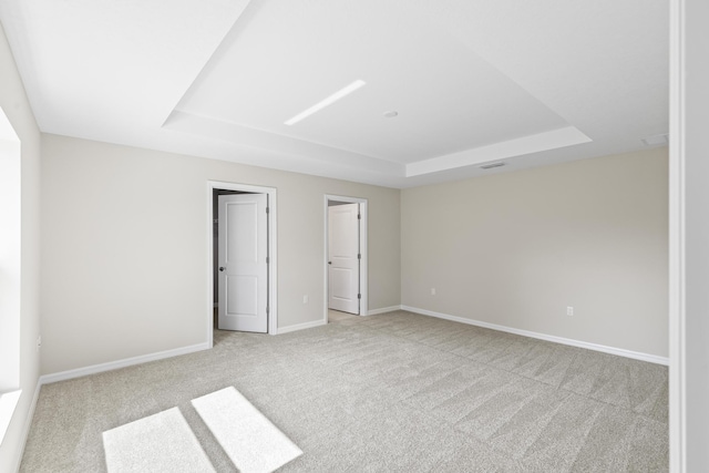 carpeted empty room with a tray ceiling