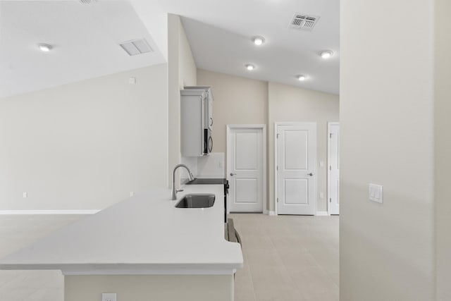 kitchen with lofted ceiling, range, kitchen peninsula, and sink