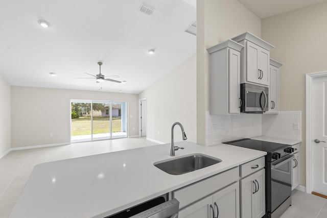 kitchen featuring sink, appliances with stainless steel finishes, gray cabinets, ceiling fan, and backsplash