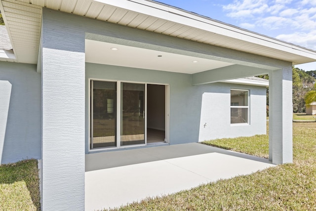 view of exterior entry featuring a yard and a patio area