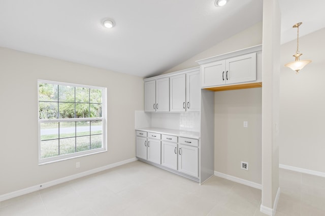 kitchen featuring pendant lighting, white cabinetry, vaulted ceiling, and backsplash