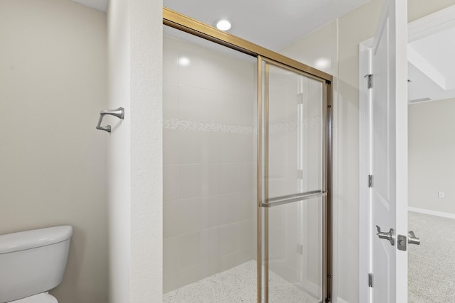 bathroom featuring a shower with door and toilet