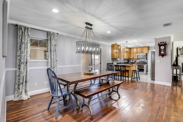 dining room featuring ornamental molding, a textured ceiling, dark wood-type flooring, and a notable chandelier