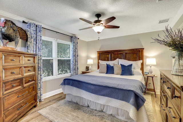 bedroom with ceiling fan, light hardwood / wood-style flooring, a textured ceiling, and ornamental molding