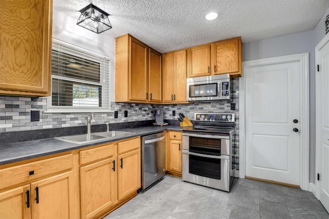 kitchen with decorative backsplash, sink, a textured ceiling, and appliances with stainless steel finishes