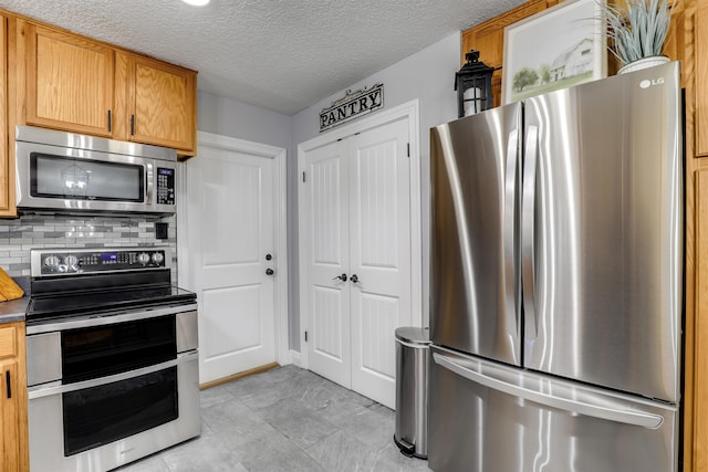 kitchen featuring a textured ceiling, stainless steel appliances, and backsplash