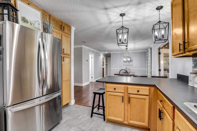 kitchen featuring kitchen peninsula, crown molding, a notable chandelier, stainless steel refrigerator, and hanging light fixtures