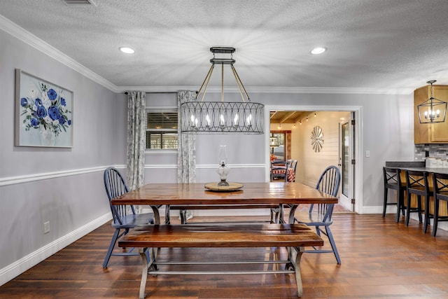 dining room featuring a chandelier, dark wood-type flooring, a textured ceiling, and ornamental molding