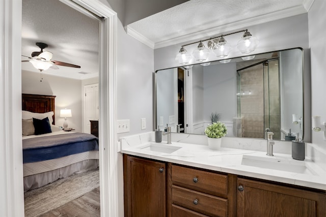 bathroom with a textured ceiling, a shower with door, ceiling fan, crown molding, and wood-type flooring