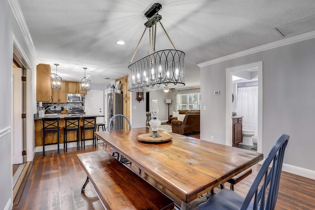 dining space featuring a textured ceiling, crown molding, dark wood-type flooring, and a chandelier